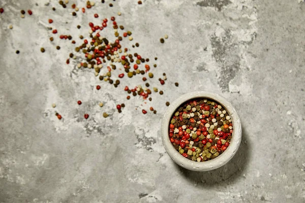 Gri desenli arka planda gri bir kasede renkli pepercorn..