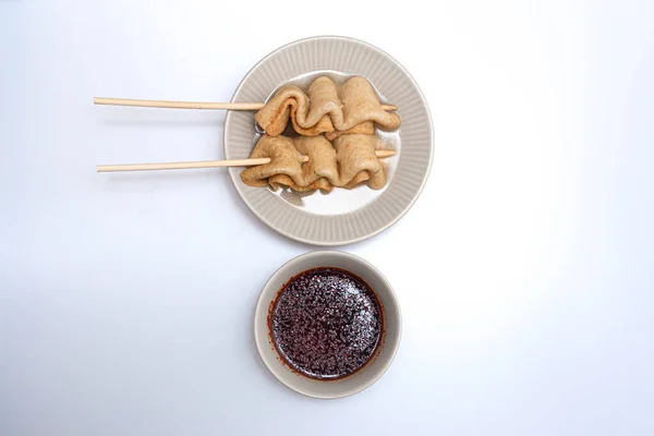 Beyaz arka planda bir kasede balık köftesi şişleri.