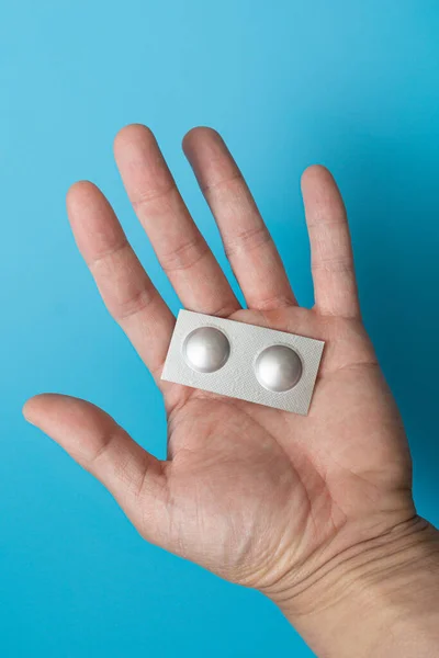 Mavi arka planda tek tek paketlenmiş haplar.