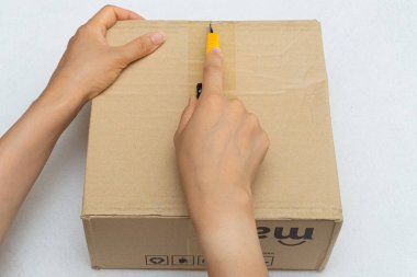 Unboxing the courier box with a cutter knife