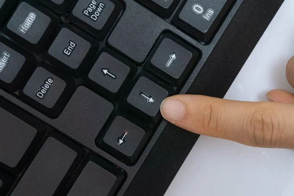 A woman\'s finger holding a computer keyboard