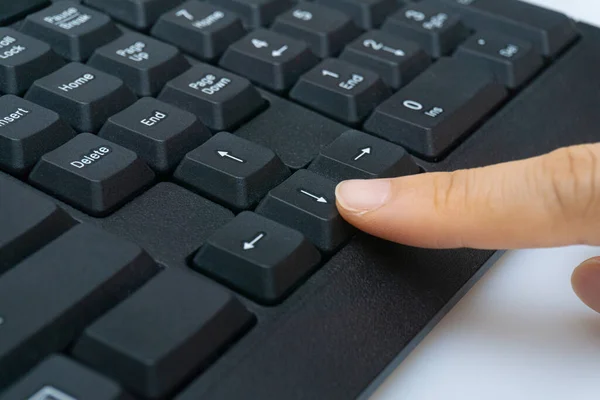 A woman's finger holding a computer keyboard