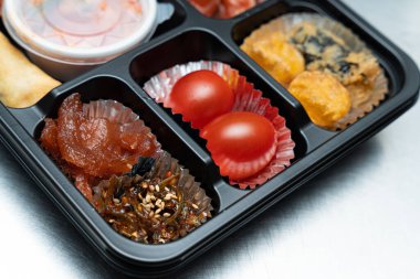 A delicious-looking lunch box with a variety of side dishes, fruits and tempura