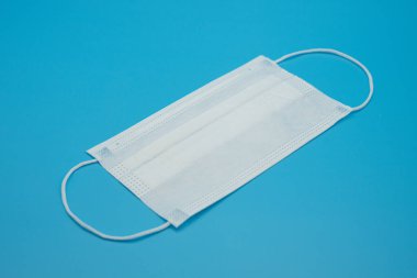 Mavi arkaplanda çeşitli renklerde tek kullanımlık koruyucu maskeler