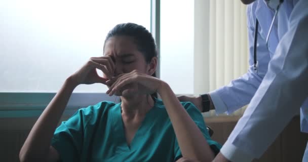 病院では 車椅子の働き過ぎの若い女性が目を閉じてすすり泣きます 医者は彼女を安心させ助けが必要かどうか彼女と話をした — ストック動画