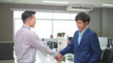 Ofiste, Asyalı bir işadamı el sıkışıyor. Müzakereler tamamlandıktan sonra, ortaklık anlaşması başarılı oldu..