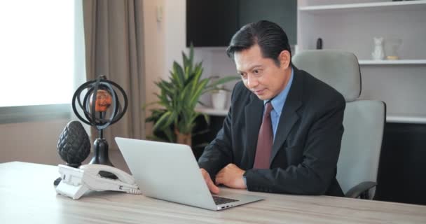 集中的な専門家の仕事のためにオフィスでラップトップを使用してアジアのビジネスマン — ストック動画
