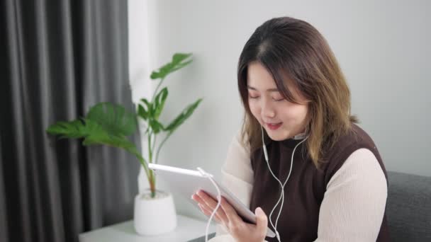 亚洲妇女使用平板电脑交谈和讨论 在家里的客厅里与顾客举行电话会议 在家工作 — 图库视频影像