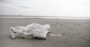 Plastik bir çanta kirliliğini deniz sahiline kapatın. Ekolojik konsept, plaj kirliliği. Sahilde çöp..