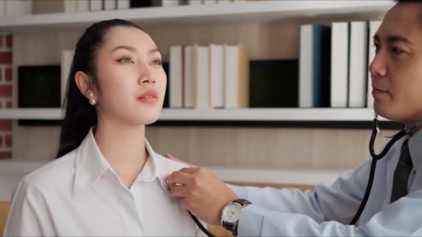 診療所で女性の肺と心臓を検査する聴診器を使用して 医療制服を着たプロのアジアの男性医師 女性患者 医療だ 医療相談 — ストック動画