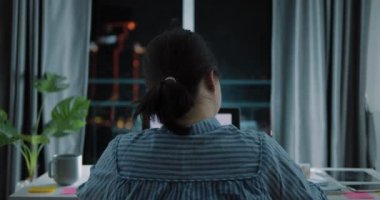 Serbest çalışan Asyalı bir kadının gece geç saatlerde dizüstü bilgisayarda Bokeh şehir manzaralı arka planı, evde ya da modern otelde fazla mesai yapan bir kadın..