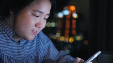 Asyalı bir kadın evde cep telefonu mutluluğuyla cep telefonuyla mesaj atıyor..