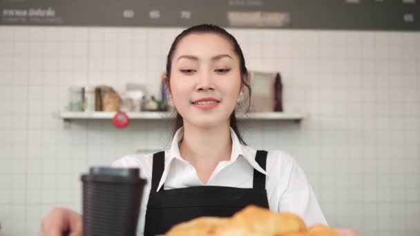 Όμορφη Ασιατική Γυναίκα Barista Κρατά Ζεστό Καφέ Και Ψωμί Χαμογελώντας — Αρχείο Βίντεο