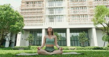 Spor giyimli Asyalı genç bir kadın açık hava yeşil parkında yoga yapıyor. Sağlıklı, egzersiz, fitness ve yaşam tarzı konsepti. Yoga ve meditasyon sağlık için iyi faydalıdır.