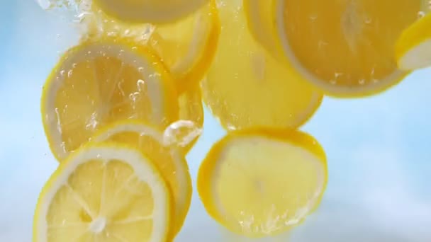 Slow Motion Fresh Yellow Lemon Slices Falling Water Splash Blue — Vídeo de Stock