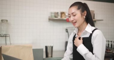 Asyalı bayan garson kasiyer bilgisayardaki müşteriden internetten kahve ve fırın siparişi alıyor. Küçük işletme sahibi ve part-time iş kavramı