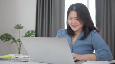 Mutlu Asyalı kadın ellerini kaldırmış, eğleniyor, dizüstü bilgisayarda çalışan güzel genç kız, başarı işini kutluyor.
