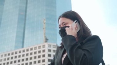 Şehir merkezinde yüz maskesi takan Asyalı iş kadınları telefonla konuşuyor. Cep telefonuyla telefon dinleyen genç iş kadınları.