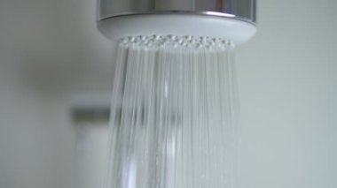 Duş başlığındaki su damlalarını kapatın. Yavaş çekim banyoda duş başlığını açıyor..