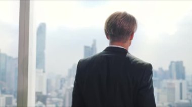 Pencereden dışarı bakan genç bir iş adamı. Tamamen odaklanmış durumda..