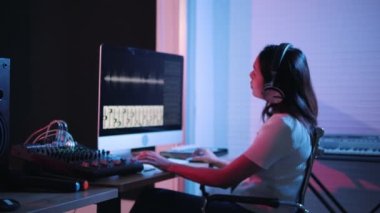 Müzik yapım stüdyosu. Yapımcı. Kayıt stüdyosunda çalışan bir kadın bilgisayar ve mikserle ses kayıt stüdyosunda müzik yaratıyor. Müzik üretimi.