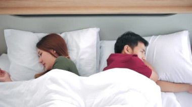 Yatakta yatan mutsuz Asyalı çift çözülmemiş ilişki sorunları yaşıyor. Otel, seyahat, ilişkiler ve cinsel sorunlar konsepti. İlişkide sorunlar yaşayan genç bir çift..