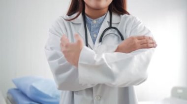 Dost canlısı Asyalı doktor kadın portresi beyaz laboratuvar önlüğü ve kameraya gülümseyen steteskop takıyor. Hastanedeki ofisinde silah zoruyla duruyor..