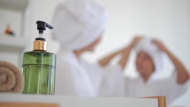 Anne ve kızının yüzüne serum sürmesi, aile güzelliği tedavisi. Sabah bakım rutini. Gençlerin cilt sorunları. Serum şişesinden bulanık.