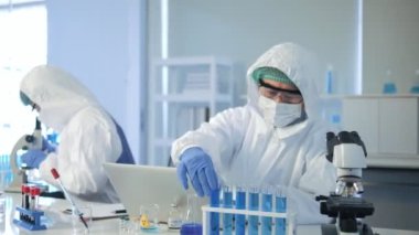 Test mavi tüplü Asyalı bilim adamı klinik laboratuvarında araştırma yapıyor. Bilim, kimya, teknoloji, biyoloji ve insan konsepti.