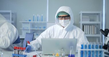 Asyalı bilim adamı analizi laboratuvarda sonuç veriyor. Bilim adamı araştırma yapıyor. Modern Laboratuvarda Deney Yöneticisi..