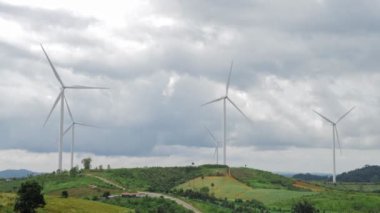 Dağdaki çayır tarlasında rüzgar türbini inşaatı, gökyüzünde yağmur bulutu, enerji tasarrufu kavramı. alternatif enerji üretiliyor