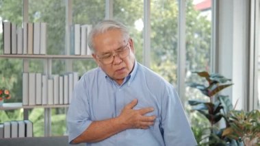 Kalp krizinden muzdarip göğüs ağrısı olan yaşlı bir Asyalı. Akut ağrıdan göğsünü tutan bir adam. Kalp krizi semptomları, sağlık hizmetleri ve tıbbi konsept.