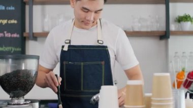 Kafede kahve makinesiyle çalışan Asyalı genç bir barista..
