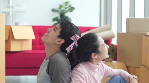 若い魅力的な幸せなアジアのカップルの男性と女性の肖像紙パックボックスストレージと新しい家の中で空の家に移動するに座っている 若い結婚したアジア人移住ホームコンセプト — ストック動画