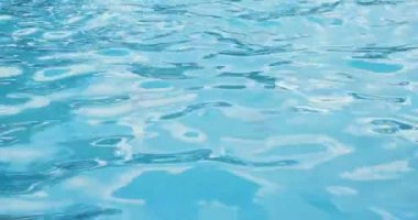 Bir havuz arka planında şeffaf mavi suyun yüzeyinde dalgalanmalar.