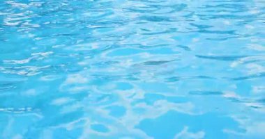 Bir havuz arka planında şeffaf mavi suyun yüzeyinde dalgalanmalar.