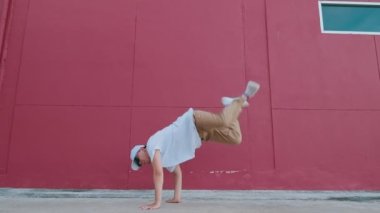 Dansçı adam sokak duvarında serbest dans ederek eğleniyor. Modern yaşam tarzı, mutluluk konsepti. Break dans, hiphop dansı, sokak dansı..