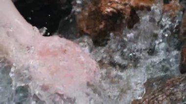 Dağlarda bir şelalenin altında eller. Şelale ellere dökülen saf su damlaları.