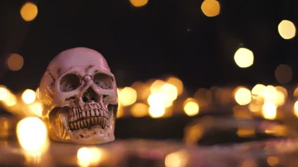 人間のプラスチック製の頭蓋骨に光のボケの背景がある ハロウィーンのテーマを背景にしたホリデーハロウィーン コピースペース — ストック動画