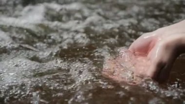 Orman nehrinde ya da gölde temiz bir şelale tutarak. Ellere dökülen saf su damlaları. Su damlaları, su kaynakları, toprak, çevre. Doğal kaynakların korunması.