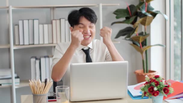 年轻的亚洲商人看着手提电脑屏幕 兴奋地听到了难以置信的好消息 开心的情绪主管庆祝收到吸引人的投资通知 — 图库视频影像