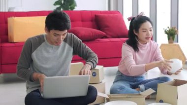 Evde çalışan Asyalı çift işyeri sahibi iş yerinde paketleme kutusuyla internet üzerinden alışveriş yapan KOBİ girişimcisi veya çevrimiçi satış konsepti.