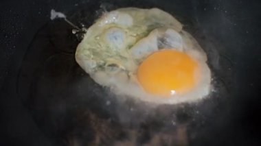 Sıcak tavada kızarmış yumurta. Yumurta kızgın tavaya düşer. Yavaş çekim.