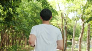 Yeşil halk parkında koşan çekici bir genç adam. Spor yapıyor. Sağlıklı yaşam tarzının tadını çıkarıyor..