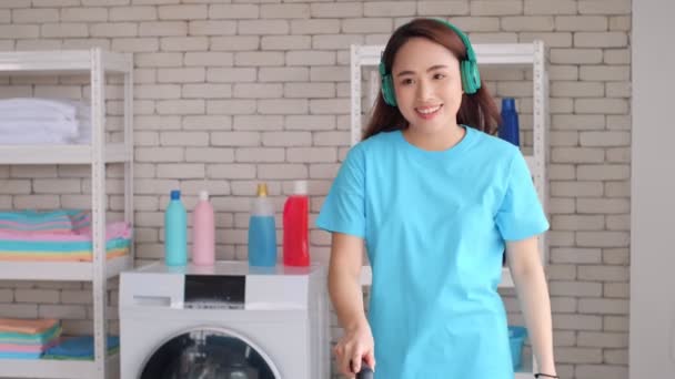 Mujer Asiática Joven Está Escuchando Música Sus Auriculares Sala Limpieza — Vídeo de stock