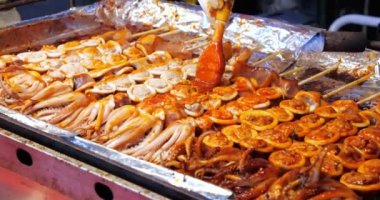 Baharatlı ateşte pişmiş kalamar satay. Şişte ızgara kalamar, lezzetli sokak yemekleri, yanan yemekler, meşale pişirme..