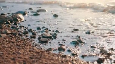 Kumsalda çakıl taşı kumları yavaşça hareket ediyor..