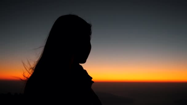 ゆっくりとした動きで日の出に山の頂上に夕日を見て希望の女性 夢の少女を感じやる気のシルエット地平線で希望を見て — ストック動画