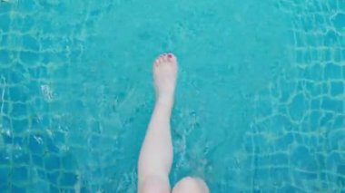 Güneşli bir günde tropikal yüzme havuzunda dinlenen kız, su turizminin en güzel kadın bacakları manzarası.