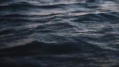 Alacakaranlık akşamında deniz dalgası, alçak açı görüntüsü, rahatsız edici koyu mavi okyanus suyu arka planı. Yavaş çekim